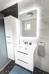 a white bathroom with a sink and a mirror at La longère des cerisiers  +3 photos
