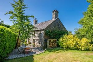 an old stone house with a picnic table in a yard at Llys-Derwin in Dolbenmaen