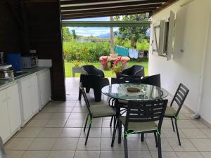 Una cocina y un comedor con una mesa de cristal y sillas. en Dans un coin de verdure, en Lamentin