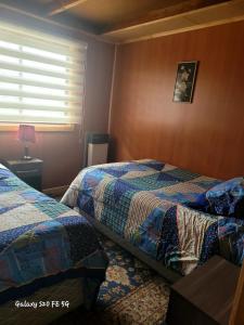 a hotel room with two beds and a window at Hostal familiar traveltour El Campesino in Puerto Natales