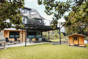 ein Haus mit einer umlaufenden Terrasse mit einer Hundehütte in der Unterkunft Apartment Morgentau, mit Aussicht in Wieda & großzügigen Garten in Walkenried