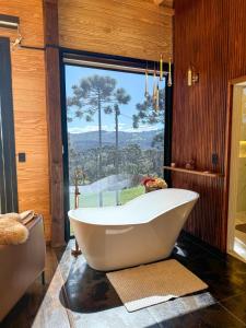 a bath tub in a bathroom with a large window at Cabana Bergamo, Villa Itália - Urubici in Urubici