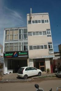 un coche blanco estacionado frente a un edificio alto en Hotel Ashwini Lodge en Mysore