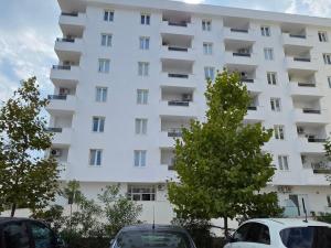 a white building with cars parked in front of it at Nova Apartments Golem in Golem