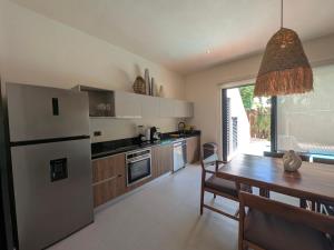 a kitchen with a table and a white refrigerator at Luxury 4 Bedroom Villa with Private Pool in Tulum