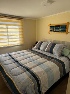 Una cama grande en un dormitorio con ventana. en Entre Dunas y Caracolas, en Punta de Choros