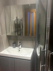 Un baño con un lavabo blanco y un espejo. en KAYUMBA Properties LTD, en Leeds
