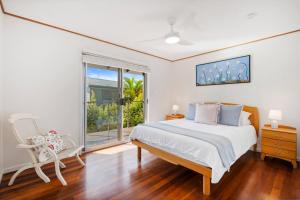 a bedroom with a bed and a window and a chair at Ocean View Koala Beach Retreat in Pottsville