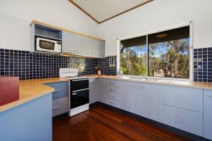 a kitchen with blue and white cabinets and a window at Ocean View Koala Beach Retreat in Pottsville