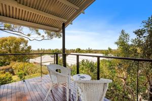 a balcony with two chairs and a view of the woods at Ocean View Koala Beach Retreat in Pottsville