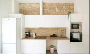 een keuken met witte kasten en een bakstenen muur bij Life in the Center of Valencia - Fast Wiffi in Valencia