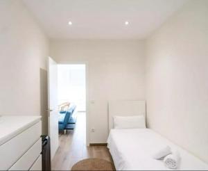 een witte slaapkamer met een bed en een blauwe stoel bij Life in the Center of Valencia - Fast Wiffi in Valencia