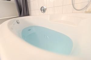 una vasca da bagno bianca con un oggetto blu dentro di Ferienwohnung Villa Waldeck, Alleinlage - Eigene Sonnenterrasse - 70 m2 a Bad Kissingen Altre 9 foto