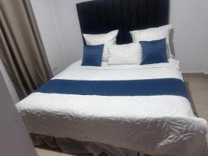 Una cama grande con almohadas azules y blancas. en Kachimam Luxury Apartment, en Kitwe