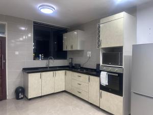 una cocina con fregadero y refrigerador en Kachimam Luxury Apartment, en Kitwe
