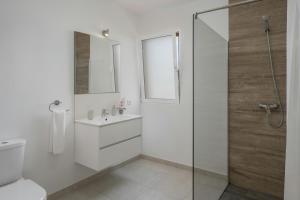 a white bathroom with a shower and a sink at La Maison Dorée in Porto Santo +25 photos