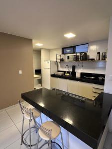a kitchen with a black counter and two chairs at Apart amplo, equipado e cama king in João Pessoa