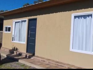 a house with a blue door and two windows at El Refugio Tapalque in Tapalqué
