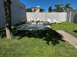 a backyard with a pool with two chairs and a tree at La Luján Ayres de Campo in Luján