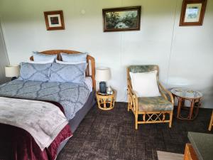 a bedroom with a bed and a chair at Glenwood Akaroa Bush Retreat - Kanuka Hut in Akaroa