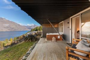 a house with a deck with a view of the water at Summit Serenity in Queenstown