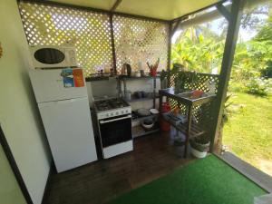 a small kitchen with a refrigerator and a stove at Fare Mahagariki in Haapiti