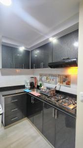 a kitchen with black cabinets and a stove top oven at Apartmento Úbate in Ubaté