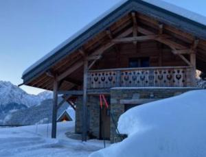 a log cabin with a balcony in the snow at Chalet Fontaines Huez in LʼHuez