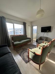 a living room with a couch and chairs and a tv at Croeso! in Puerto Madryn