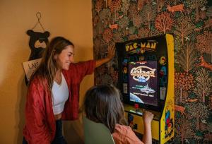 eine Frau steht neben einem Mann, der ein Videospiel spielt in der Unterkunft Hot Tub-Game Room-Nintendo Switch-BBQ in Big Bear City Airport