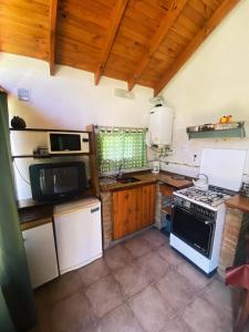 a kitchen with a stove and a microwave at Cabaña Los Angeles in Villa General Belgrano