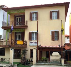 Akanthos Hotel في إيريسوس: مبنى أصفر كبير مع نوافذ وعلم
