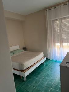 a bedroom with a bed and a window and green tiles at Lucia House mare Nettuno in Nettuno