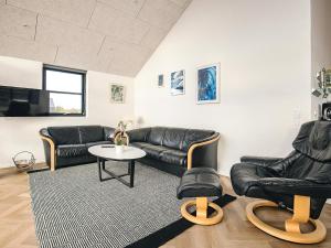 ein Wohnzimmer mit schwarzen Ledermöbeln und einem Tisch in der Unterkunft 5 star holiday home in Løkken in Løkken