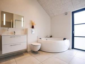ein Badezimmer mit Badewanne, Toilette und Waschbecken in der Unterkunft 5 star holiday home in Løkken in Løkken + 25 Fotos