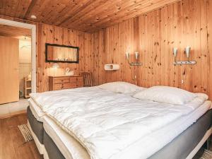 a bedroom with a large white bed in a wooden wall at 4 star holiday home in Hals in Hals