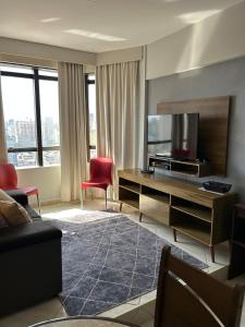 a living room with a television and a red chair at Ap Aconchegante no Centro! in Campinas
