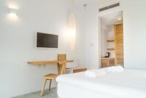 two beds in a room with a desk and a tv at Semeli in Kokkari