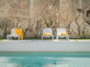 three chairs with yellow cushions sitting next to a pool at Semeli in Kokkari