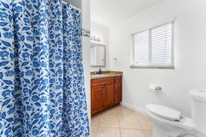 La salle de bains est pourvue de toilettes et d'un rideau de douche bleu et blanc. dans l'établissement Jupiter Coastal Cottage, à Jupiter 11 autres photos