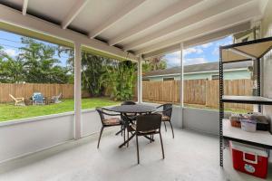 un porche grillagé avec une table et des chaises dans l'établissement Jupiter Coastal Cottage, à Jupiter