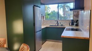 a kitchen with green cabinets and a stainless steel refrigerator at On The Jetty Lake-view Apartment in Long Jetty +15 photos