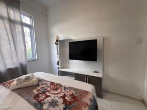a bedroom with a bed with a television on the wall at Apartment perto Praia e Metro, Melhor Localização in Rio de Janeiro