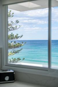 a window with a view of the ocean at Elegant Beachfront Retreat with Fabulous Views in Sydney