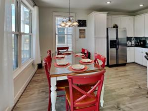 a dining room table with red chairs and a kitchen at So Serene in Galveston