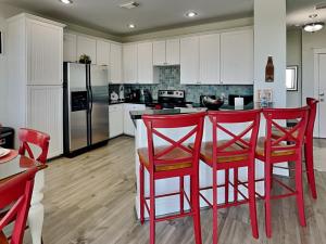 a kitchen with red bar stools and a refrigerator at So Serene in Galveston