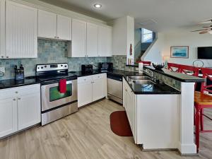 a kitchen with white cabinets and black counter tops at So Serene in Galveston +44 photos