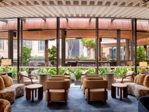 a lobby with chairs and tables and windows at Sofitel Sydney Wentworth in Sydney