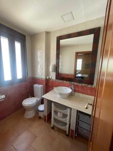 Un baño con inodoro, lavabo y espejo. en El Fontanar de Peñarrubia, en Peñarrubia