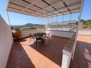 Un patio con una mesa y sillas en un tejado. en El Fontanar de Peñarrubia, en Peñarrubia